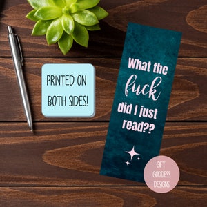 Puede incluir: Marcador de libro azul turquesa con fondo blanco y texto rosa que dice "What the fuck did I just read??". El marcador tiene un peque&ntilde;o c&iacute;rculo rosa en la parte inferior con el texto "GIFT GODDESS DESIGNS".
