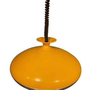 May include: A yellow pendant light with a black cord and a silver trim. The light is shaped like a dome.