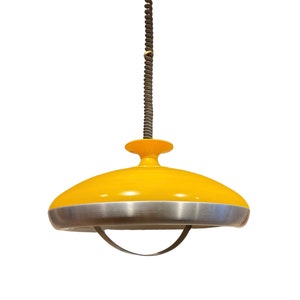 May include: A yellow and silver pendant light with a spring cord. The light has a round, saucer-shaped shade with a silver rim.