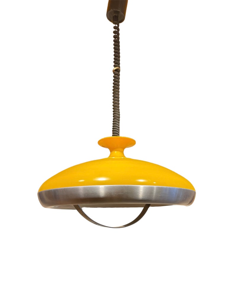 May include: A yellow and silver pendant light with a spring cord. The light has a round, saucer-shaped shade with a silver rim.
