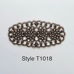 May include: Brown, oval-shaped lace doily with a floral design. The doily is made of delicate, intricately woven lace. The text "Style T1018" is printed below the doily.