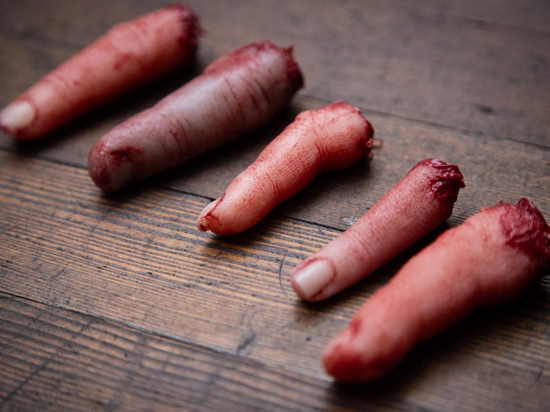 May include: Five severed, bloody fingers on a wooden surface. The fingers are realistic and detailed, with visible blood and flesh.