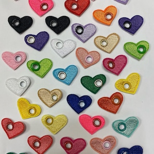 May include: Assortment of colorful felt heart-shaped tags with metal eyelets. The hearts are in various colors, including red, pink, blue, green, yellow, orange, purple, and white.