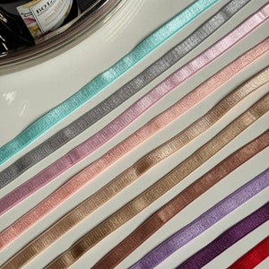 Può includere: Assortimento di 10 nastri elastici di diversi colori con un leggero luccichio. I colori sono turchese, argento, rosa, pesca, beige, oro, marrone, lavanda, viola e rosso.