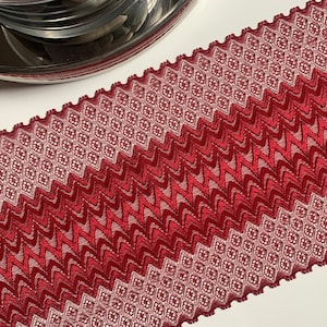 May include: Red and white patterned lace trim with a zig-zag design. The trim is made of a soft, stretchy material and is perfect for adding a touch of elegance to any project.