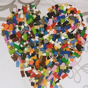 May include: A large heart-shaped pile of colorful Lego bricks in various shapes and sizes.