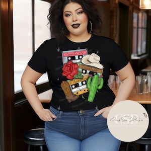 May include: Black t-shirt with a graphic design of cassette tapes, a cactus, a rose, and a cowboy hat. The cassette tapes have the titles "Como La Flor", "Desvelado", and "Te Aprovechas" with the years 1992, 1995, and 1995.