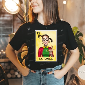 May include: A black t-shirt with a colorful illustration of a woman with pigtails and glasses. The illustration is in the style of a traditional Mexican Loteria card. The text "72 LA TOXICA" is printed below the illustration.