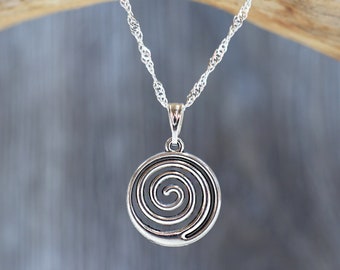May include: A silver necklace with a spiral pendant. The pendant is round and has a detailed spiral design.