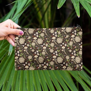 May include: A brown fabric pouch with a zipper closure. The pouch has a repeating pattern of white dice with green vines and white flowers on a dark brown background.