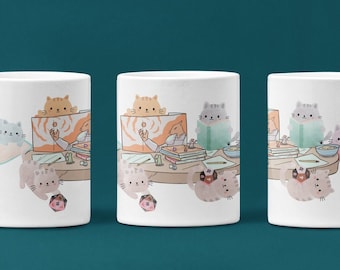 Pode incluir: Caneca de cerâmica branca com uma ilustração colorida de gatos lendo e relaxando em torno de uma mesa. Os gatos estão em várias poses, alguns estão sentados, outros estão deitados e alguns estão olhando para a câmera. A caneca é um ótimo presente para os amantes de gatos.