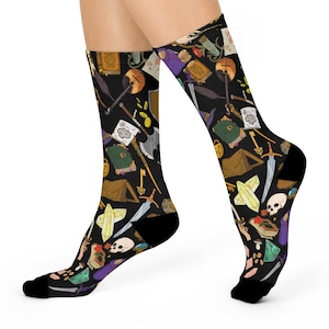 May include: A pair of black socks with a colorful pattern of fantasy and role-playing game themed items, including books, swords, keys, and crystals.