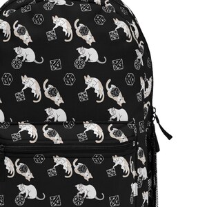 May include: Black backpack with a repeating pattern of white cats playing with dice.