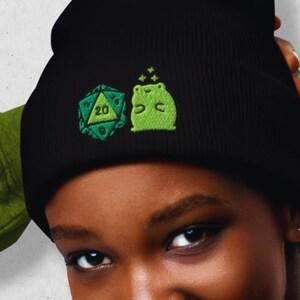 May include: A black beanie with a green 20-sided die and a green frog with stars embroidered on it.