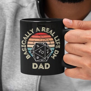 May include: Black coffee mug with a retro design featuring a 20-sided die and the text "Basically a Real Life DM Dad".