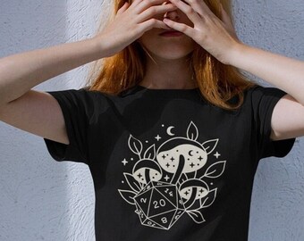 Puede incluir: Camiseta negra con un gráfico blanco de un dado de 20 caras rodeado de setas y estrellas.
