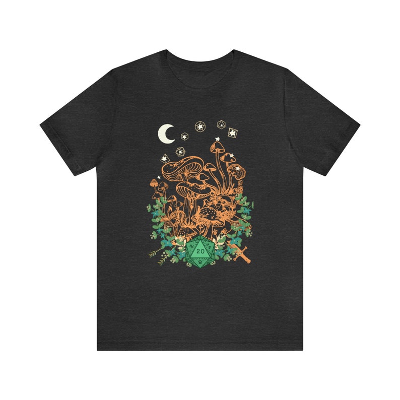 May include: A dark heather grey t-shirt with a graphic of mushrooms, a crescent moon, stars, and a green 20-sided die. The graphic is surrounded by green foliage and a sword.