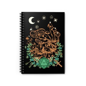 May include: A black spiral notebook with a design of mushrooms, a crescent moon, and a green twenty-sided die. The mushrooms are outlined in orange and the die has white numbers.