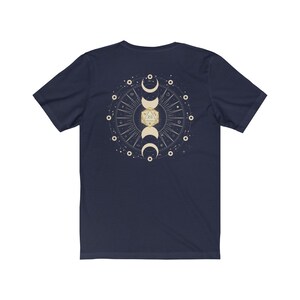 May include: Navy blue t-shirt with a gold and white design of a 20-sided die surrounded by moons and stars.