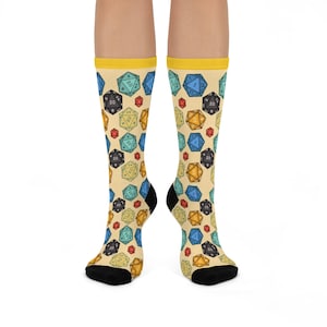 May include: A pair of yellow, cream, and blue socks with a pattern of colorful dice. The socks are knee-high and have a black toe and heel.