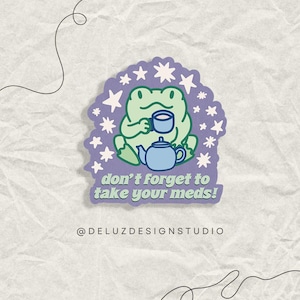 May include: A sticker featuring a cartoon frog holding a teacup and teapot. The frog is green, with a light blue teapot and teacup. The sticker has the text "don't forget to take your meds!" and is surrounded by stars.