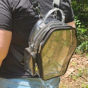 Mochila transparente con forma de ataúd y correas ajustables e intercambiables.