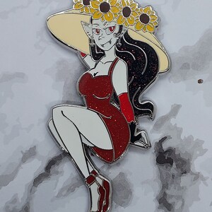 May include: A red glitter dress with a black and white design, worn by a figure with a large, wide-brimmed hat adorned with yellow sunflowers. The figure has red eyes and long black hair.