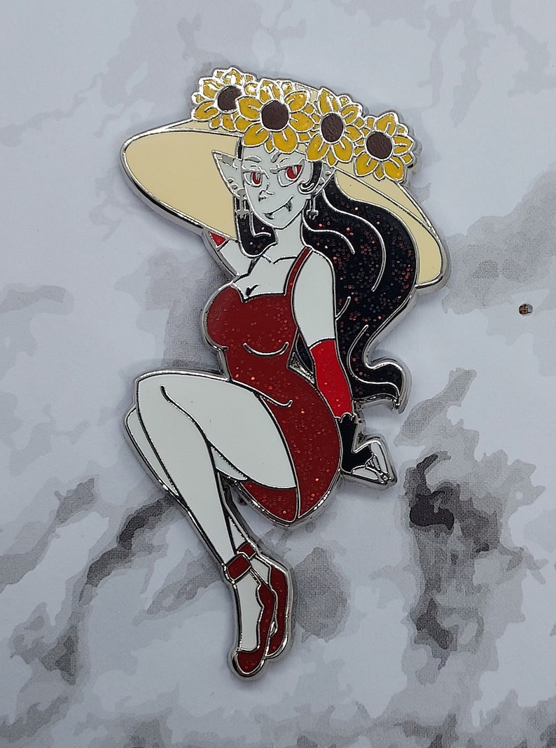 May include: A red glitter dress with a black and white design, worn by a figure with a large, wide-brimmed hat adorned with yellow sunflowers. The figure has red eyes and long black hair.
