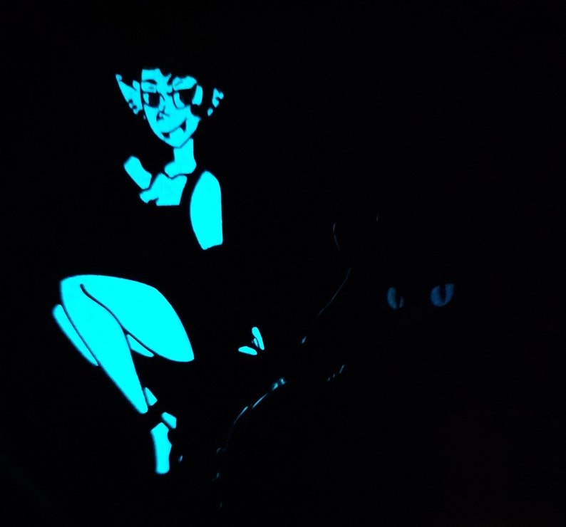 May include: A blue and black glow-in-the-dark pin featuring a woman with pointed ears and a cat with glowing eyes.