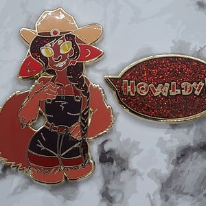 May include: A red and gold enamel pin featuring a cartoon character wearing a cowboy hat and overalls. The character has a red tail and a speech bubble that says "HOWLDY!!".
