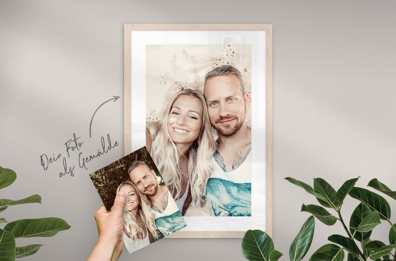 May include: A framed watercolor painting of a couple. The painting is in a light wood frame and has a white mat. The couple is smiling and looking at the camera. The background of the painting is a light brown color with white and blue watercolor splatters.