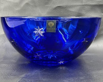 Puede incluir: Un cuenco de cristal azul oscuro con diseños de estrellas. El cuenco tiene forma redondeada y una etiqueta que dice "FABERGE CRYSTAL". Un artículo decorativo.