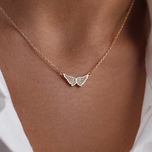 May include: A delicate gold necklace with a small, sparkling diamond wing pendant.