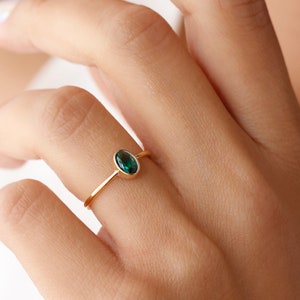 May include: A gold ring with a dark green oval gemstone.