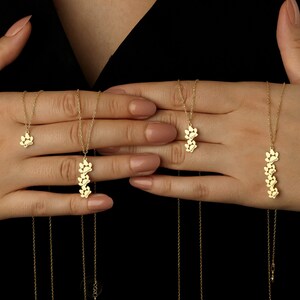 May include: Four gold necklaces with delicate paw print charms. The necklaces are layered and feature different lengths.