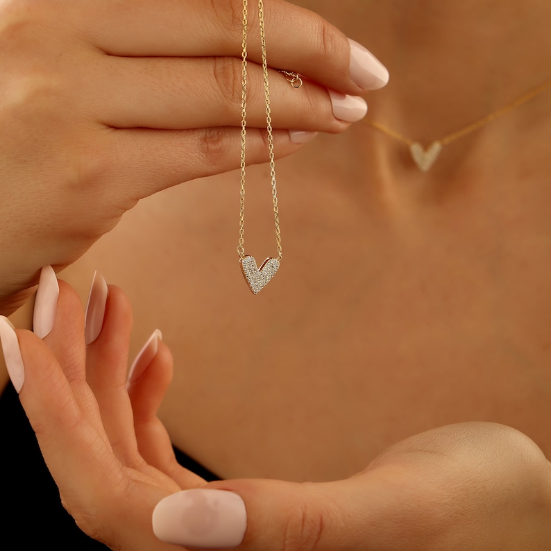 May include: A gold chain necklace with a small heart pendant encrusted with tiny diamonds.