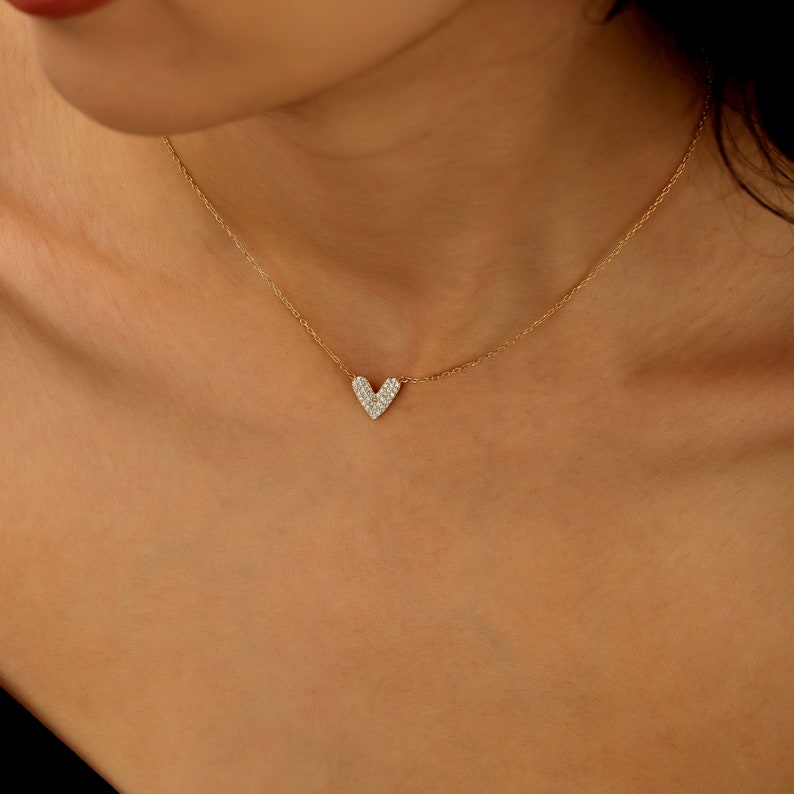 May include: A delicate gold chain necklace with a small heart pendant encrusted with sparkling diamonds.