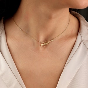 May include: A gold necklace with a violin pendant. The name "Madison" is written on the violin.