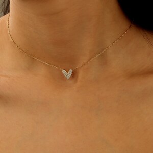 May include: A gold chain necklace with a small, heart-shaped pendant encrusted with clear cubic zirconia stones.