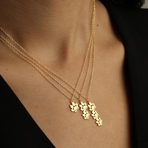 May include: Gold necklace with four paw print charms, each engraved with a different name: Millie, Charlie, Luna, and Winnie.