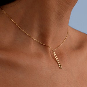 May include: A gold chain necklace with a pendant that says "Mallory" in a vertical script font.