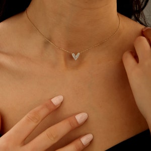 May include: A gold chain necklace with a small, heart-shaped pendant encrusted with clear cubic zirconia stones.