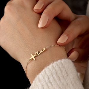 May include: Gold cross charm bracelet with the name "Olivia" engraved on it.