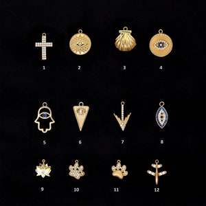 May include: Twelve gold-toned charms with various designs, including a cross, an evil eye, a seashell, a hamsa hand, a triangle, an arrow, a lotus flower, and a paw print. The charms are all set with clear and blue crystals.