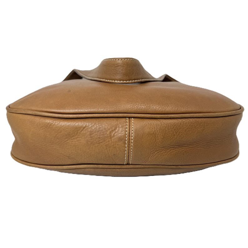 Pu&ograve; includere: Una borsa in pelle marrone chiaro con forma arrotondata e chiusura a patta. La borsa presenta cuciture a vista e una superficie strutturata. La borsa &egrave; di colore marrone chiaro.