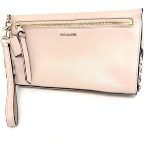 May include: A light pink leather wristlet clutch featuring a gold-tone zipper across the front, the word COACH in gold lettering, a matching leather wrist strap with a metal clasp, and a black and white snakeskin-patterned side panel detail.