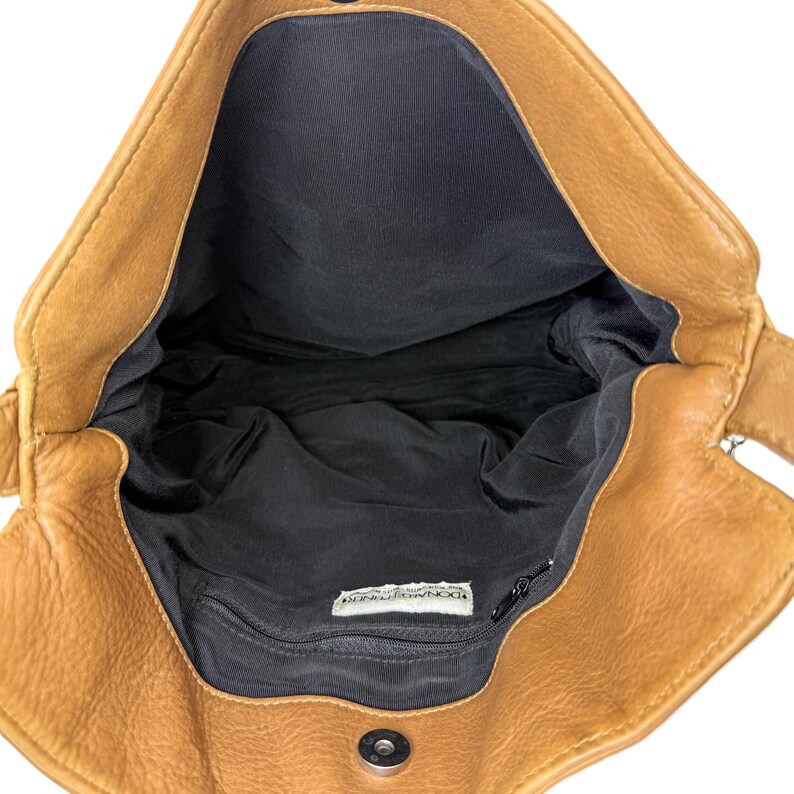 Pu&ograve; includere: Vista aperta di una borsa in pelle marrone chiaro con interno nero. La borsa ha una chiusura magnetica e una piccola tasca con cerniera all'interno. La fodera interna &egrave; nera. La borsa &egrave; vuota e pronta all'uso.