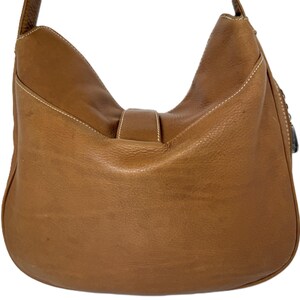Pu&ograve; includere: Una borsa a tracolla in pelle marrone chiaro con un design curvo. La borsa presenta una chiusura con fibbia e dettagli di cuciture bianche. La tracolla &egrave; attaccata nella parte superiore della borsa. La borsa &egrave; in pelle strutturata.