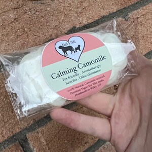 K&ouml;nnte beinhalten: Eine Packung mit zwei wei&szlig;en Sojawachs-Schmelzen mit einem rosa und gr&uuml;nen Etikett, auf dem steht: "Calming Camomile Pet friendly. Aromatherapy benefits. Odor eliminator 100% Natural, Camomile scented, Premium Vegan Soy Wax melts Handmade in Wales, UK".