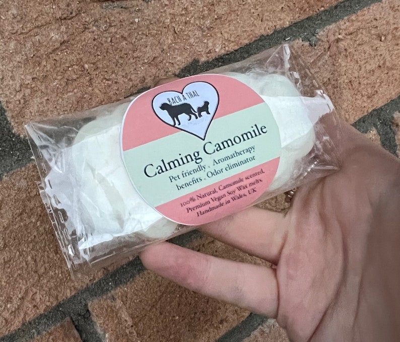 K&ouml;nnte beinhalten: Eine Packung mit zwei wei&szlig;en Sojawachs-Schmelzen mit einem rosa und gr&uuml;nen Etikett, auf dem steht: "Calming Camomile Pet friendly. Aromatherapy benefits. Odor eliminator 100% Natural, Camomile scented, Premium Vegan Soy Wax melts Handmade in Wales, UK".